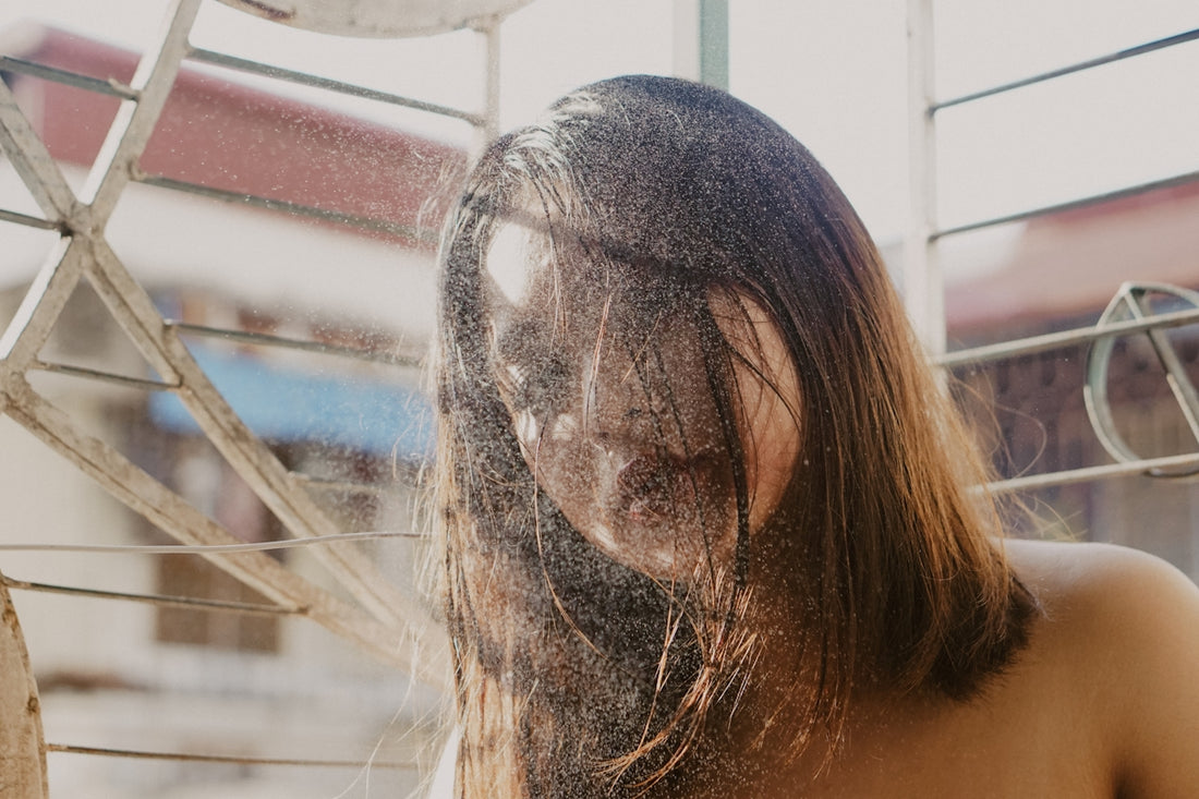 topless woman covering face with hair