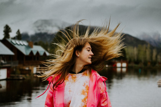 woman in white and pink floral shirt standing near body of water during daytime