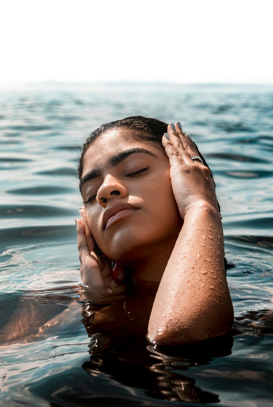 woman in water covering her face with her hands
