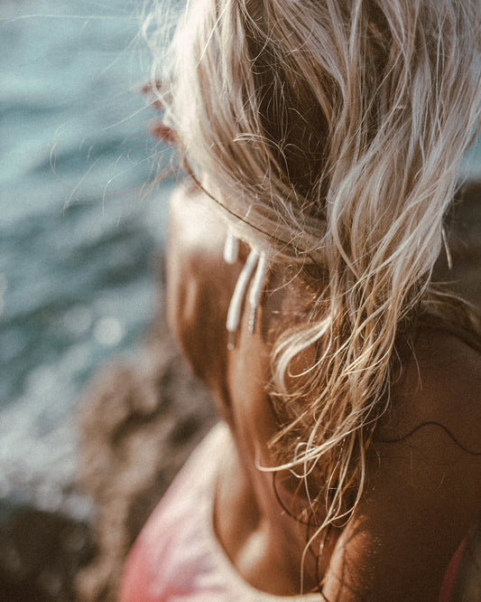 a woman sitting on a rock next to the ocean