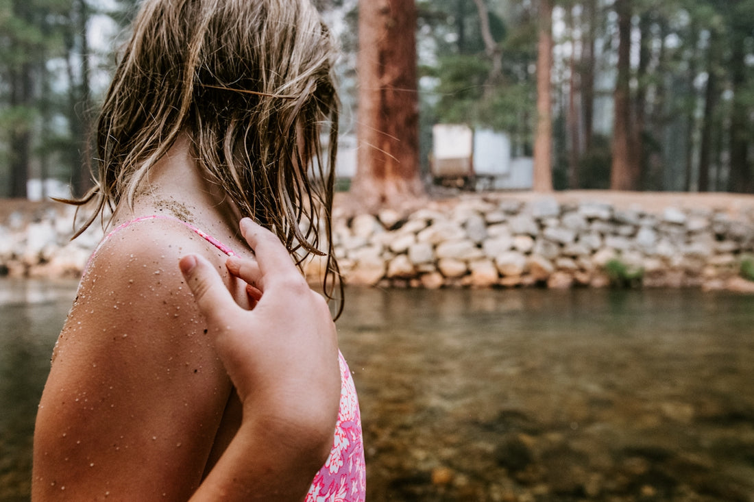 Young person with wet hair by a stream