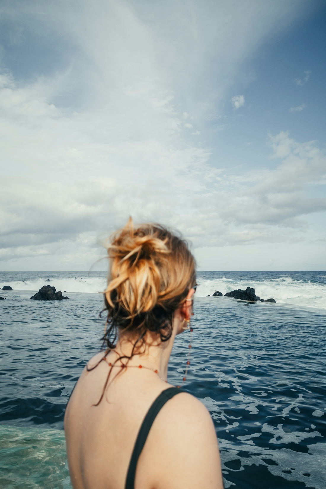 A woman standing in the water looking at the ocean